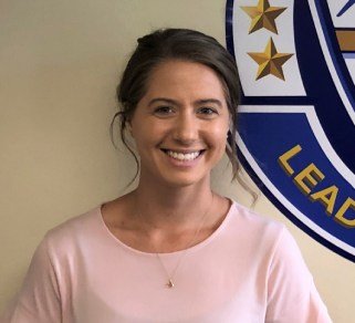 A woman smiling in front of a league logo.