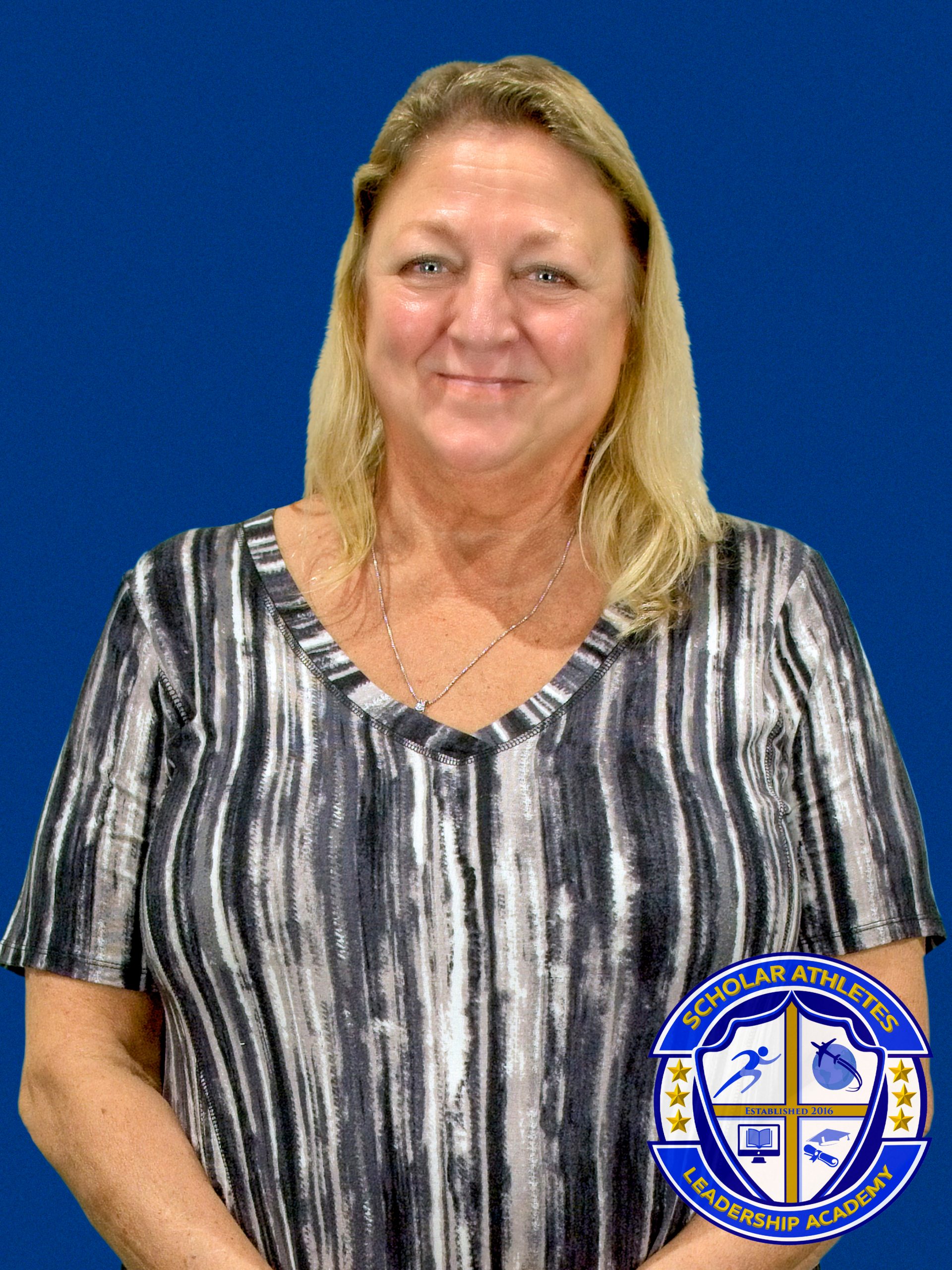 A woman standing in front of a blue background.