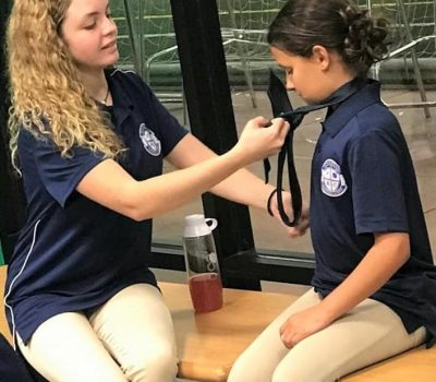 A SALA student helps another with a necktie.